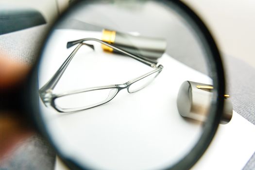 magnifier and glasses on a sheet of paper for business behind blind