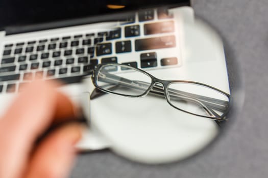 Black framed upside down glasses on the computer keyboard with a very shallow depth of field.