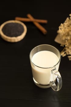 Glass of milk on black wooden background.