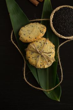 Sesame Cookies, sesame and milk on black wooden background.