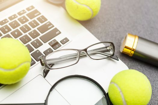 Top view of laptop, Sports Equipment, Tennis ball, Shuttlecock, glasses aon the Sports administration gray table.Business concept.