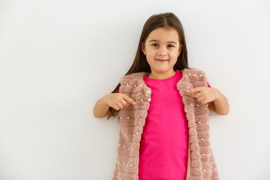 T-shirt design concept - smiling little girl in blank pink t-shirt pointing at herself