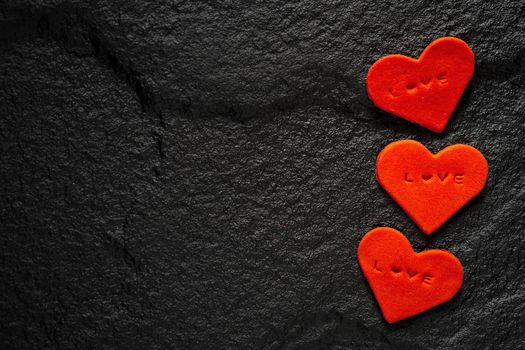 Red heart written love words placed on black stone floor.