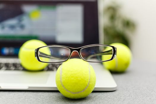 Top view of laptop, Sports Equipment, Tennis ball, glasses on the Sports administration white table.Business concept.