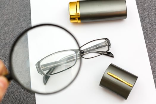 magnifier and glasses on a sheet of paper for business behind blind