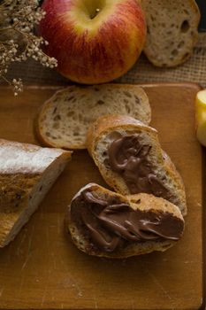 French bread baguette cut on wooden board with knife. with a chocolate butter.
