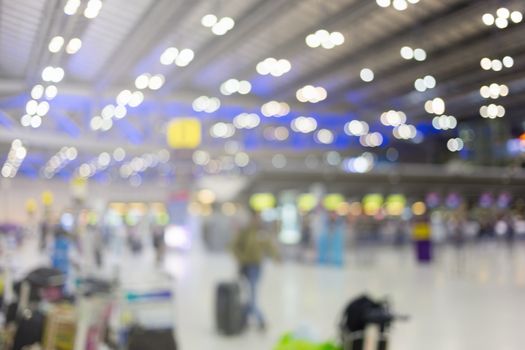 blurred image of travelers smart people walking with a luggag at airport terminal with crowd of travelling people in background. Traveling concept.