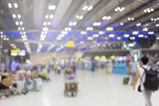 blurred image of travelers smart people walking with a luggag at airport terminal with crowd of travelling people in background. Traveling concept.