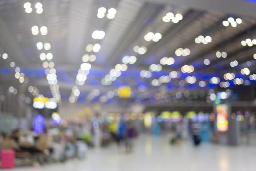 blurred image of travelers smart people walking with a luggag at airport terminal with crowd of travelling people in background. Traveling concept.