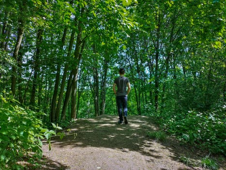 Man in t-shirt at edge of hill in park with thin trees