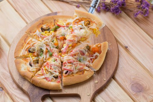 Close up of tasty homemade seafood topped pizza fusion food style on wooden tray.