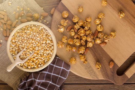 Corn kernels in wooden plates and popcorn with Caramel and almond cream on wooden table.