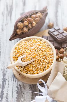 Corn kernels in wooden plates and popcorn with Caramel and chocolate cream on wooden table.