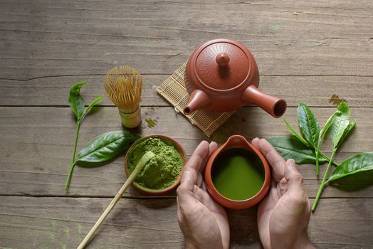 Matcha Green Tea and Japanese tea set. Ceramic teapot and a steaming cup on wooden background.