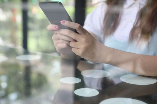 Female hand with smartphone trading stock online in coffee shop , Business concept