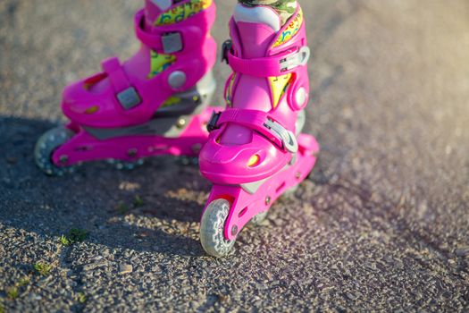Childrens feet in pink childrens rollers close-up. Roller skates for outdoor sports. Healthy lifestyle baby