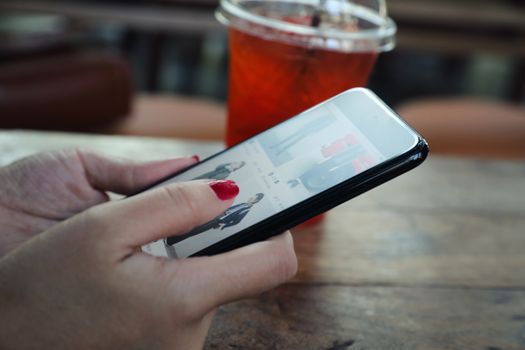 Female hand with smartphone trading stock online in outdoor coffee shop , Business concept