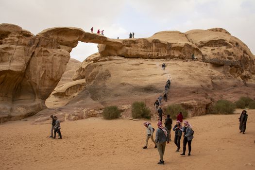 Wadi Rum, Jordan, March 2020: People, tourists, climbing the Um Frouth natural Rock Bridge