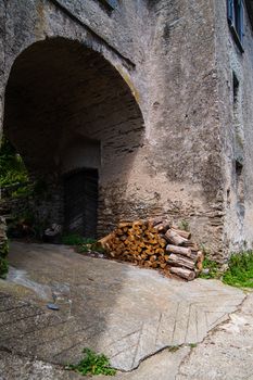 a pile of wood against the wall of an old house with a trespassing with a wooden door on the isle of Corsica in France during summertime