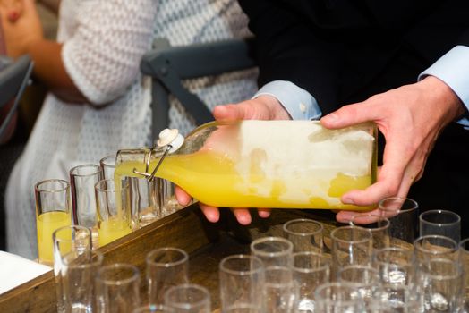 close-up of a waiter serving limoncello in glasses at a party