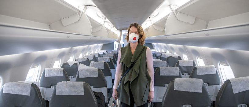 woman on board of aircraft with respirator on head. protect themselves against viral disease. People cancel travel abroad due to coronavirus.