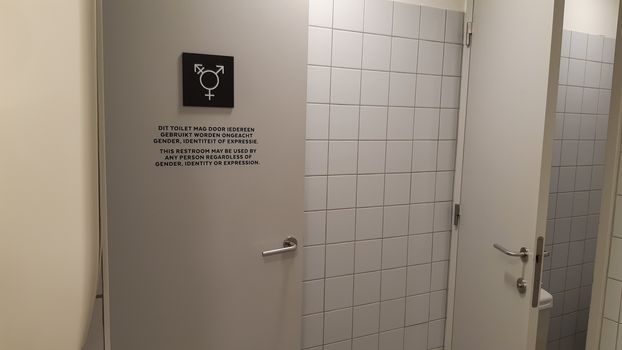 Antwerp, Belgium, May 2020: Gender neutral toilet symbol and sign on a door, in Dutch and English language