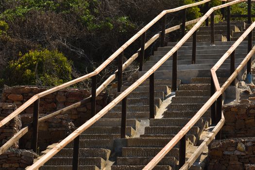 A beach exit cast concrete staircase with wooden handrails going uphill, Mossel Bay, South Africa