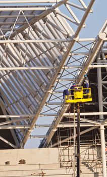 workers in air build grand stands construcion of new stadium