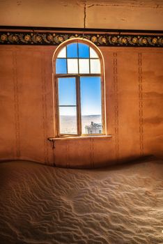 Empty room with a window and desert sand located in the ruins of the ghost town Kolmanskop in the Namib desert near Luderitz, Namibia, Southern Africa