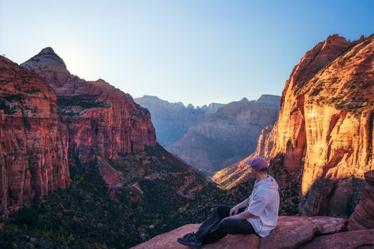 Tourist sitting at the Canyon Overlook in Zion National Park, Utah