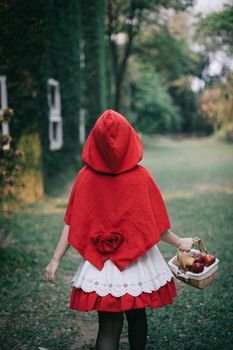 Portrait young woman with Little Red Riding Hood costume in green tree park