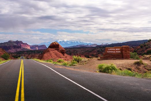 Welcome sign at the entrance to Capitol Reef National park, Utah, with snow covered Rocky Mountains in the background.