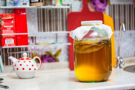 Homemade Kombucha Tea in glass jar on kitchen table - close-up with selective focus