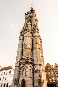 Tall medieval bell tower rising over the street with old european houses, Tournai, Walloon municipality, Belgium