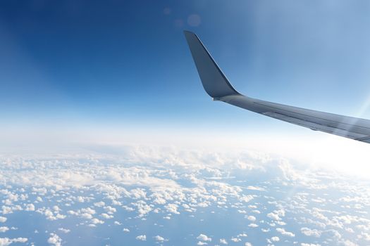 Wing of an airplane in the sky above the blue clouds