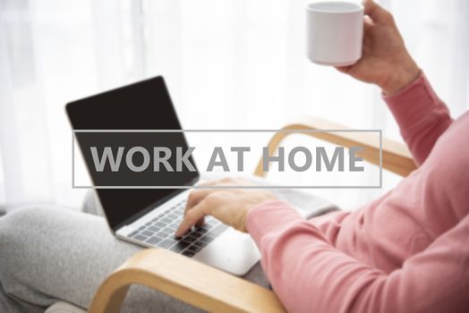 man wearing clothing comfortable working on laptop computer while sitting and drinking coffee at the living room. work at home concept.