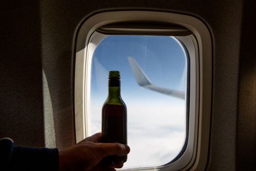 A bottle of wine opposite the porthole. Alcohol on board an airplane