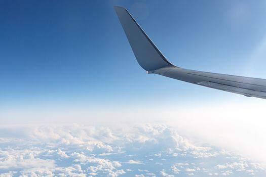 Wing of an airplane in the sky above the blue clouds