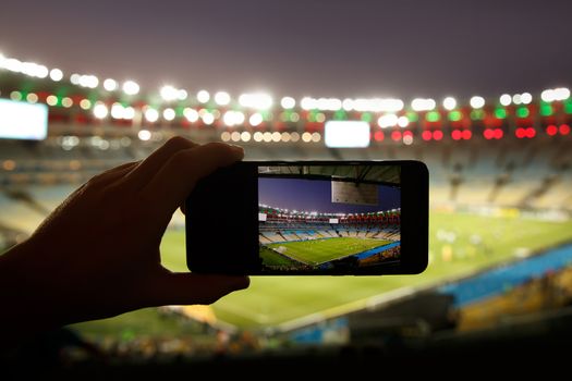 Smartphone photographing football game on the stadium.