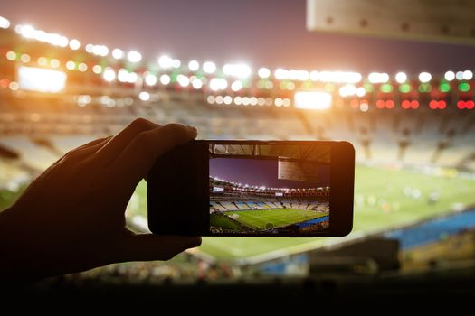 Smartphone photographing football game on the stadium.