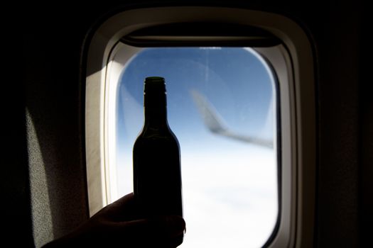 A bottle of wine opposite the porthole. Alcohol on board an airplane