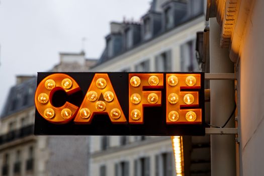 The sign from light bulbs with the word CAFE on town street