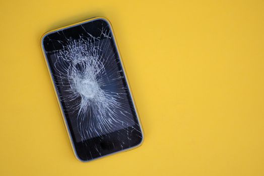 Phone with cracked screen isolated against yellow background