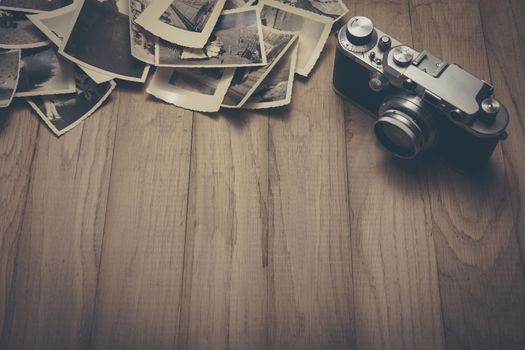 Vintage photo camera with old photos on wooden background.