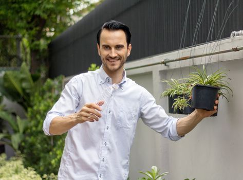 Young men watering plants in potted plants With recyclable plastic bottles When watering the plants, he twisted the plastic bottles to recycle.Young man working in the garden.