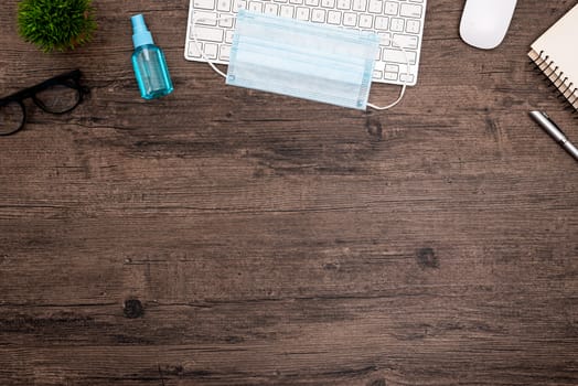 The equipment to protect COVID-19, blue mask and hand cleaner gel for preparing to work from home Isolated on wood desk.