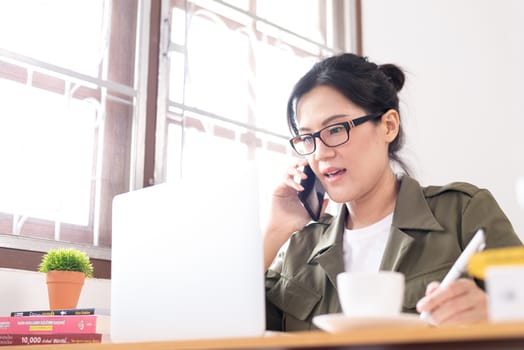 Modern young Asian woman working from home and talking with a partner about her business.