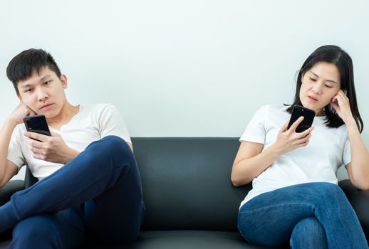 An Asian couple stays together and playing the phone with social distancing.