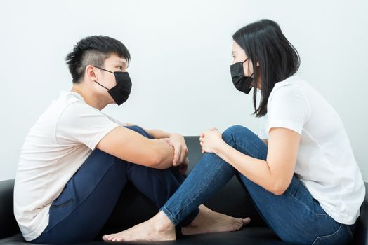 An Asian couple wearing a black mask and stays together with boring and social distancing.