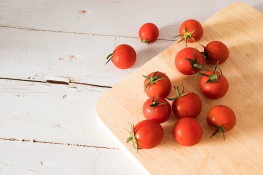 Red tomato on a cutting board wiht wooden background.